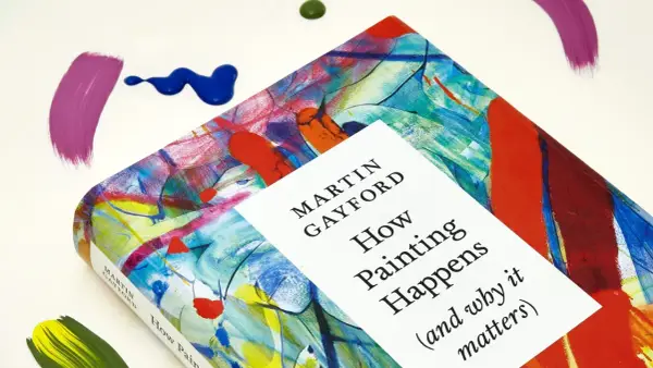 A book titled "How Painting Happens" by Martin Gayford, featuring a vibrant, abstract cover that evokes the spirit of figurative painting. Splatters of paint surround it.