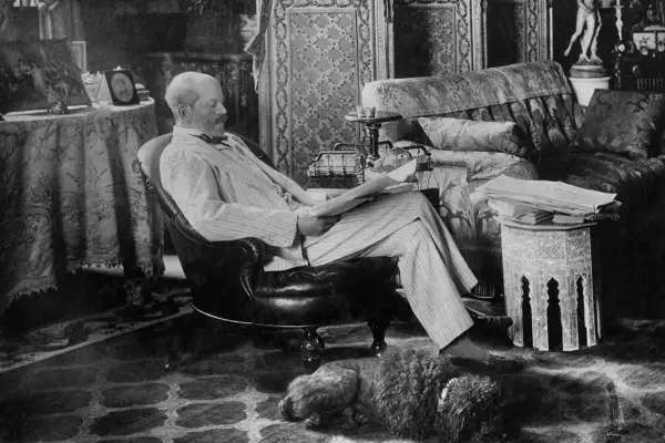 A man reads in a plush armchair, a dog sleeps nearby. The opulent room hints at the grandeur of the Rothschild art collection.