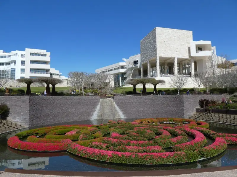 A vibrant floral maze floats in a pool before the modern architecture of the Los Angeles Center for Digital Art.